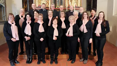 Gruppenfoto von den Chormitgliedern, alle schwarz angezogen mit hellrosa Halstüchern